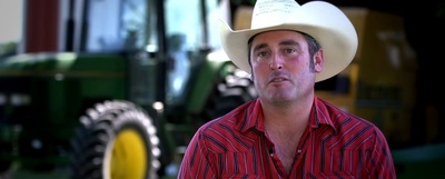 Hancock County farmer Bryan Stevens in a cowboy hat in front of a barn