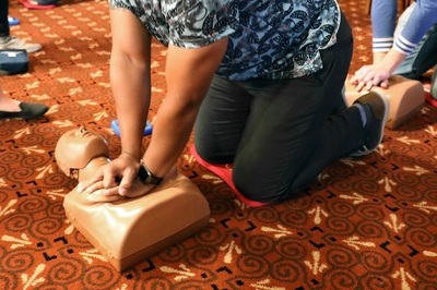 Person learning hands-only CPR practices chest compressions on a mannequin