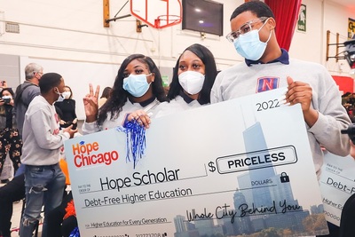 Students wearing COVID masks hold a giant check that says 