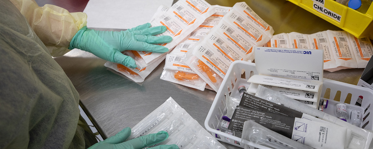 gloved hands sorting vaccine supplies on counter