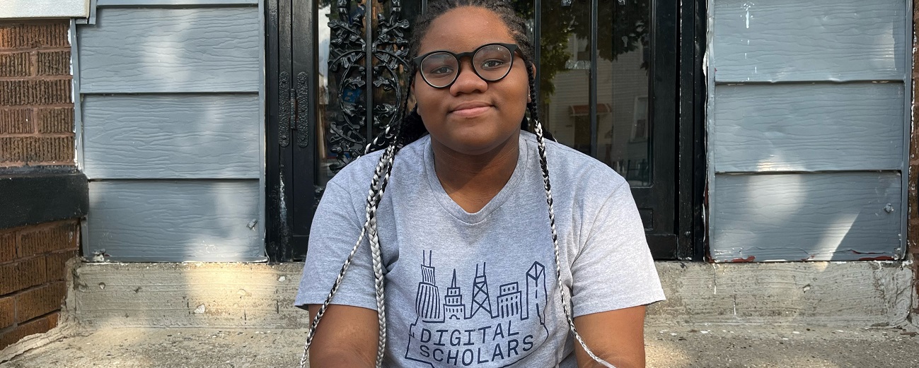 Aijah Welch sits on porch steps wearing her gray Digital Scholars t-shirt