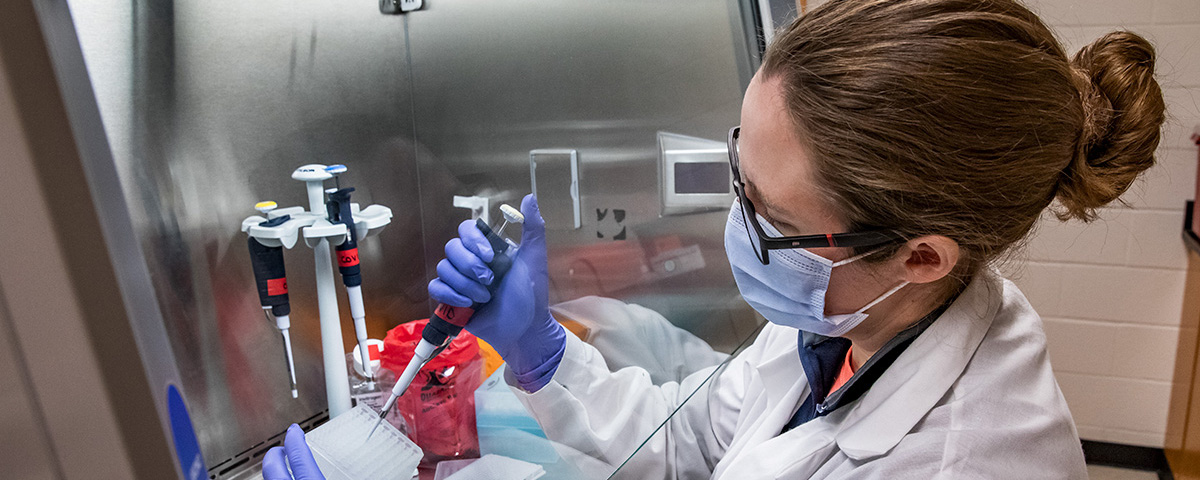 masked female researcher processing lab tests