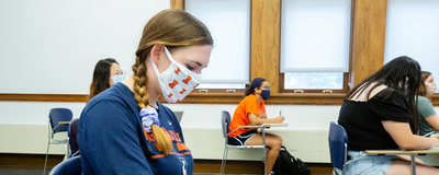 female student wearing Illini mask at desk in classroom